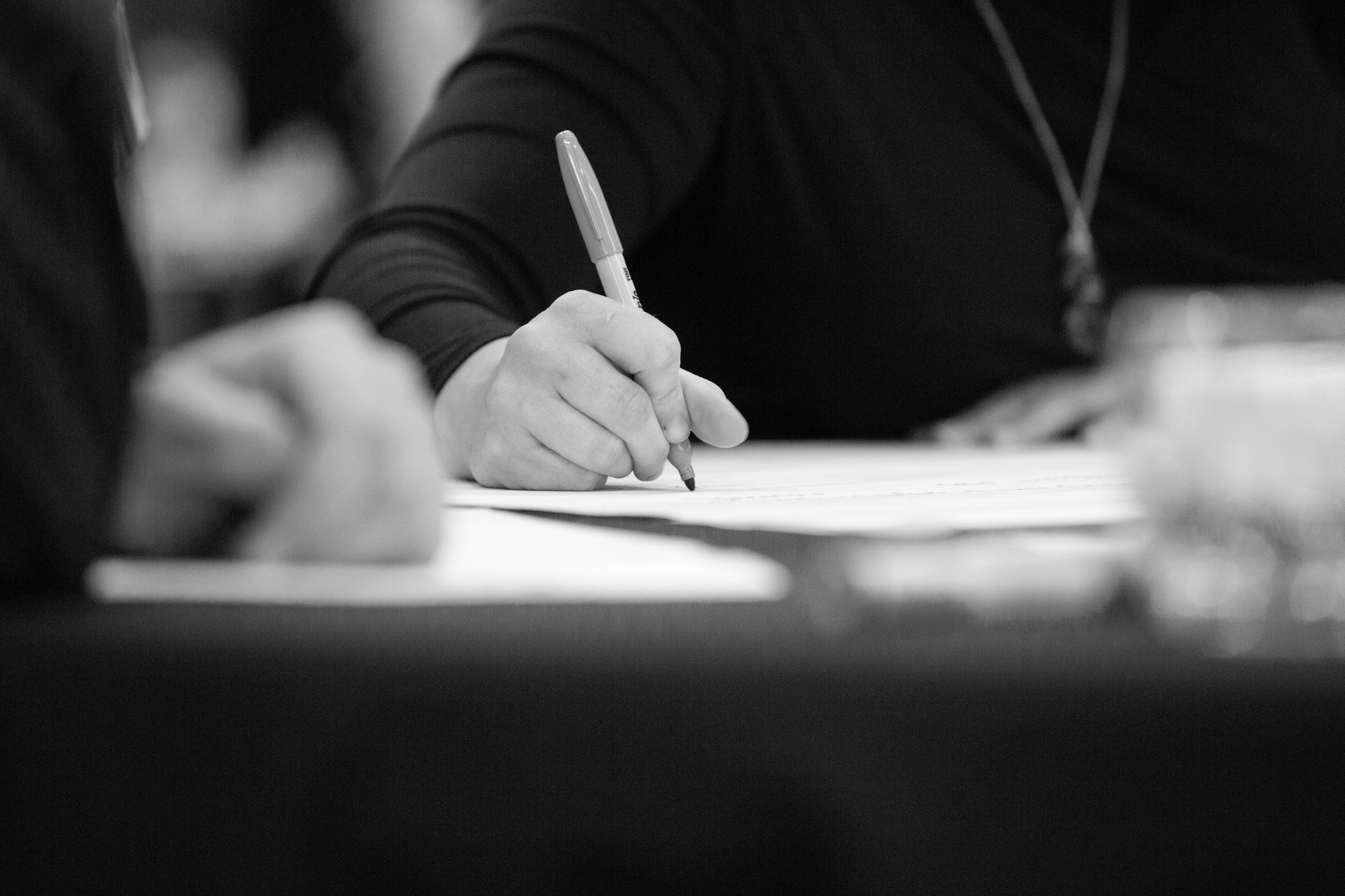 A zoomed in picture of a person writing on a piece of paper.