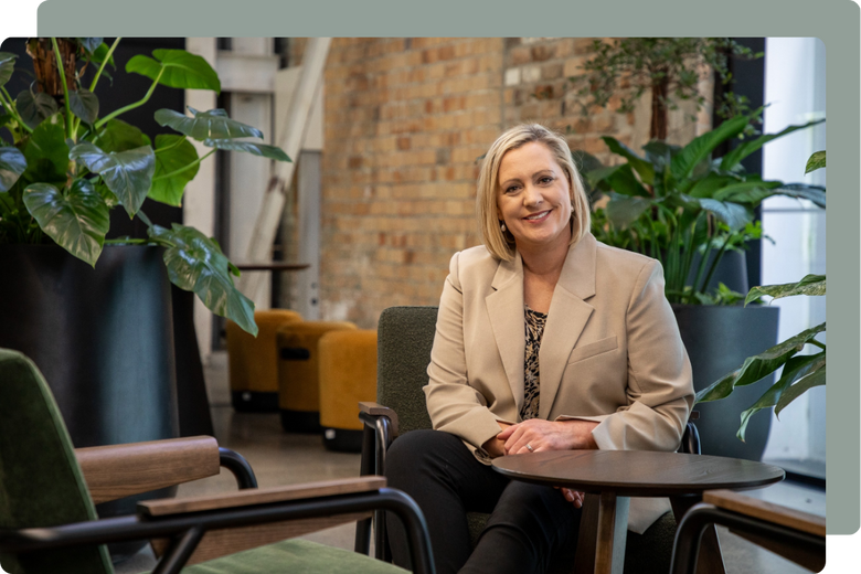 Jenny Turner smiling at the camera seated with plants in the background