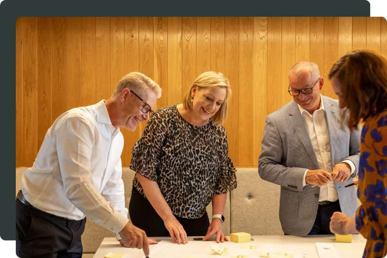 Jenny Turner and three colleagues looking at sticky notes on a white table