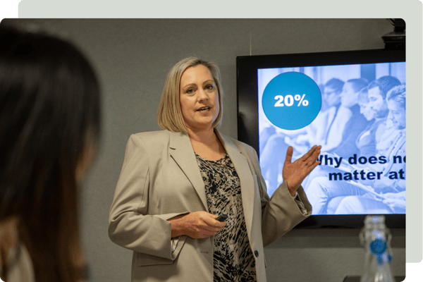 Jenny Turner wearing a beige suit speaking at a workshop educating managers on neurodiversity Jenny Turner wearing a beige suit speaking at a workshop educating managers on neurodiversity