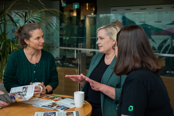 Two people listening to a third person talking in an office setting.
