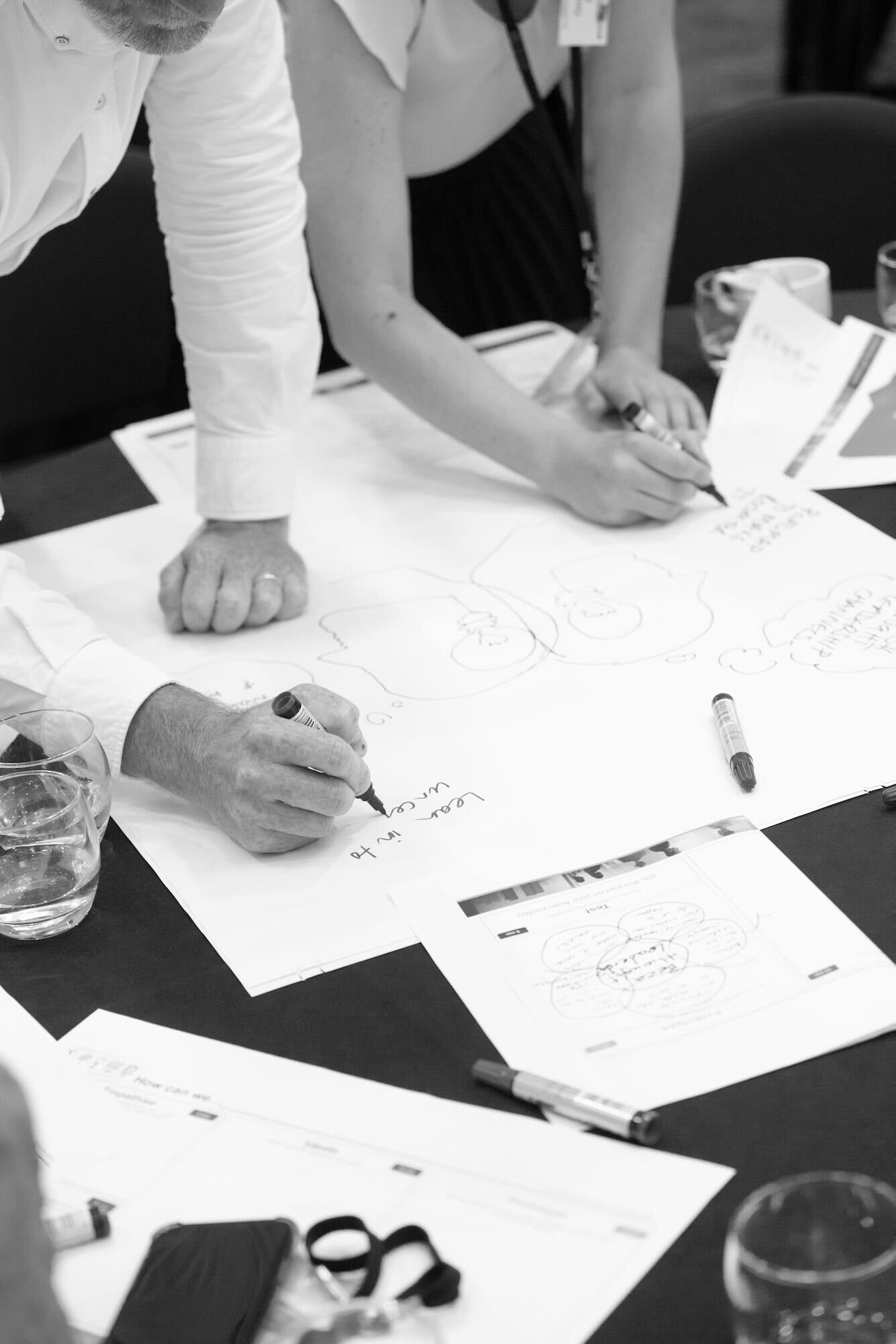 Two people writing on a large sheet of paper in a workshop. Two people writing on a large sheet of paper in a workshop.