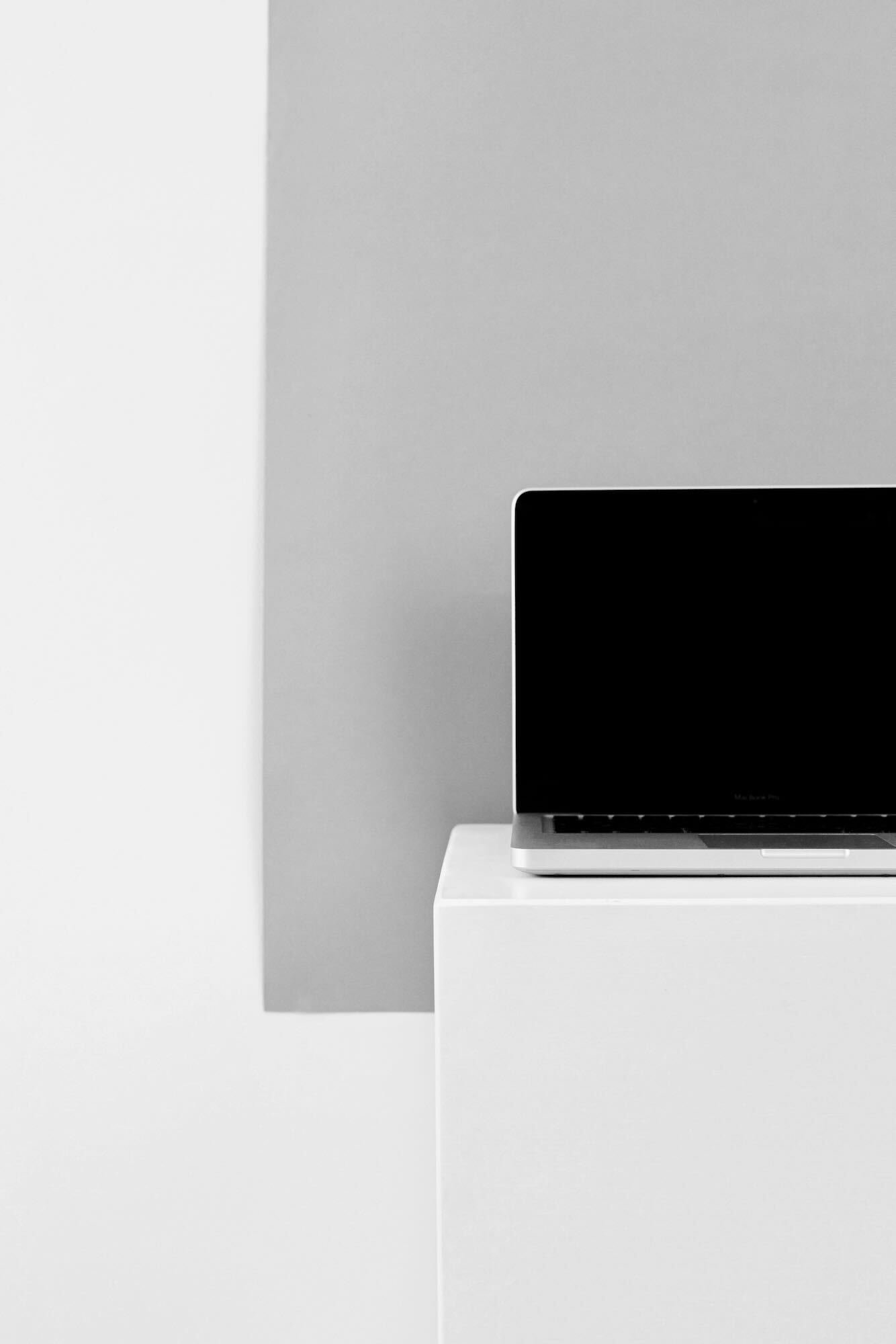 An open laptop on a white surface in front of a grey background.