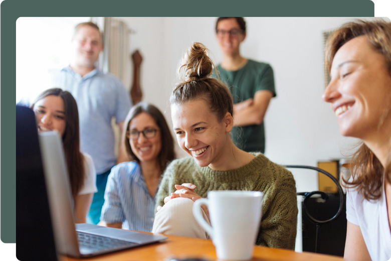 A group crowded around a laptop smiling, watching a webinar.