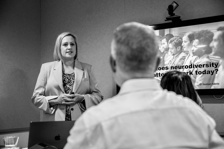 Jenny presenting a slide on neurodiversity with the back of a male participant in view, listening to her speak.