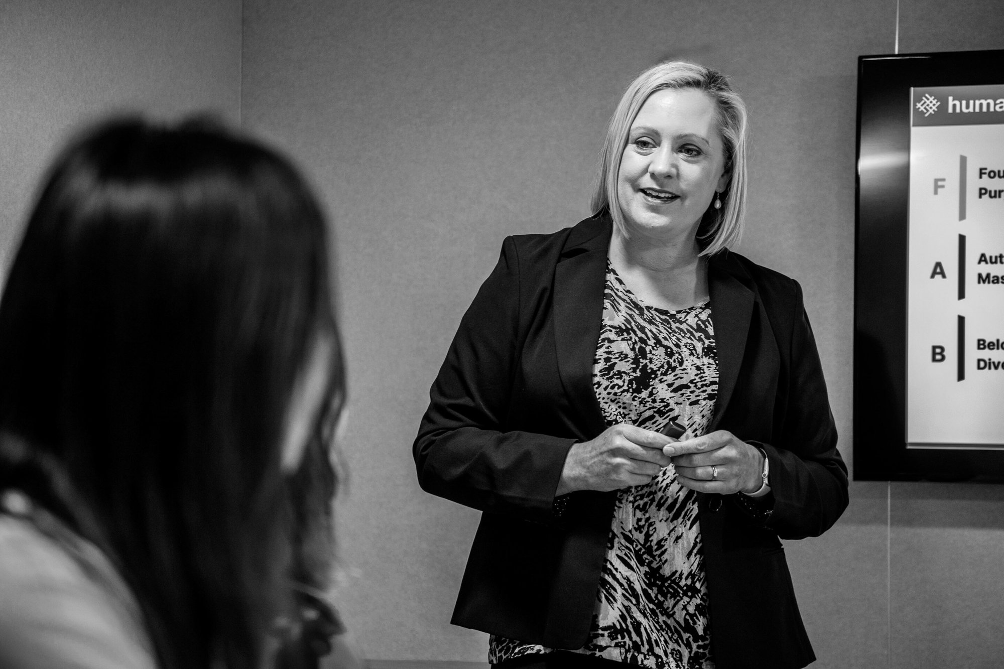 Jenny in professional attire, talking to two participants in a workshop