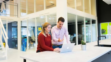Two people standing at an office kitchen having a discussion
