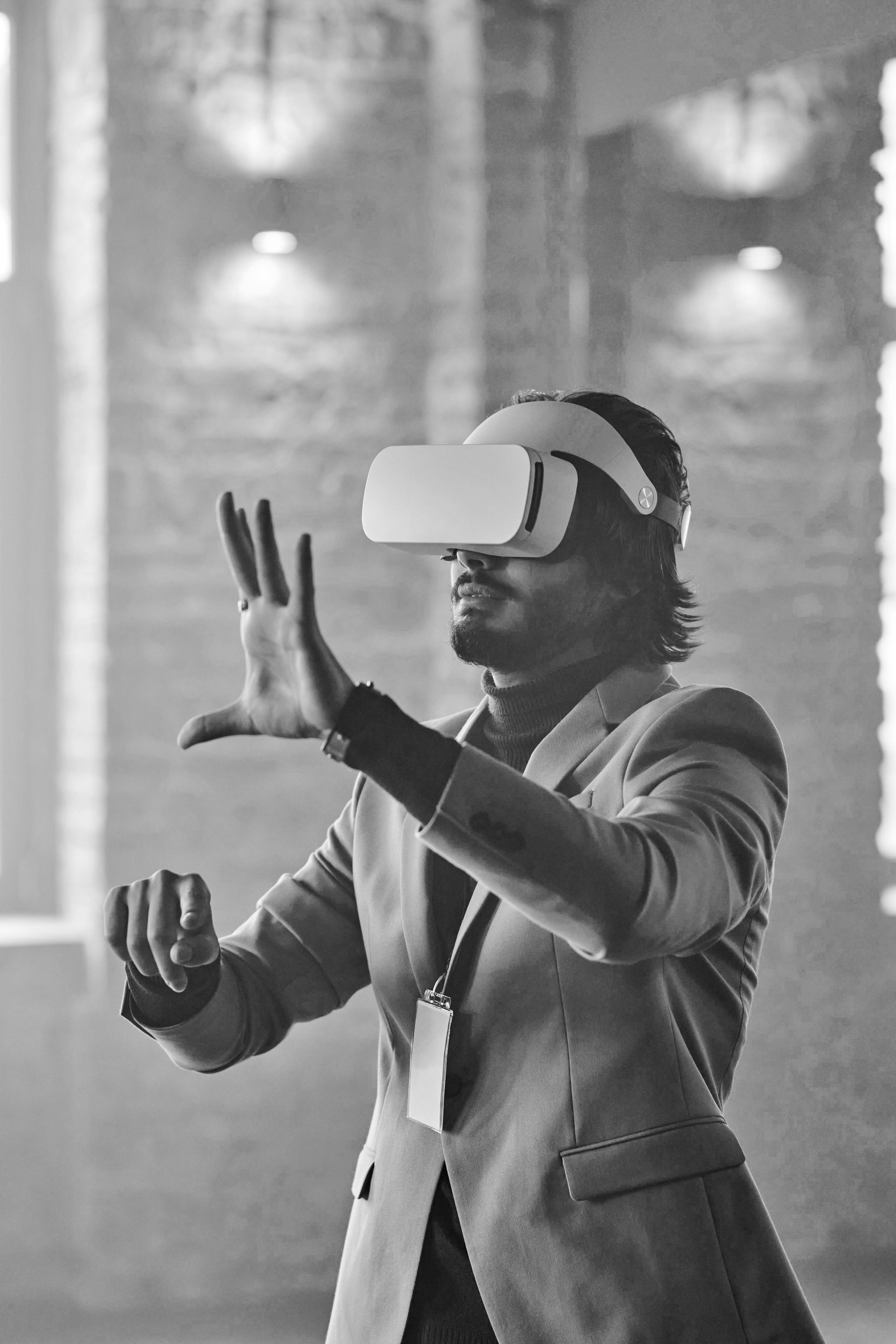 A plan in a suit with a VR headset on and his hands up interacting with it