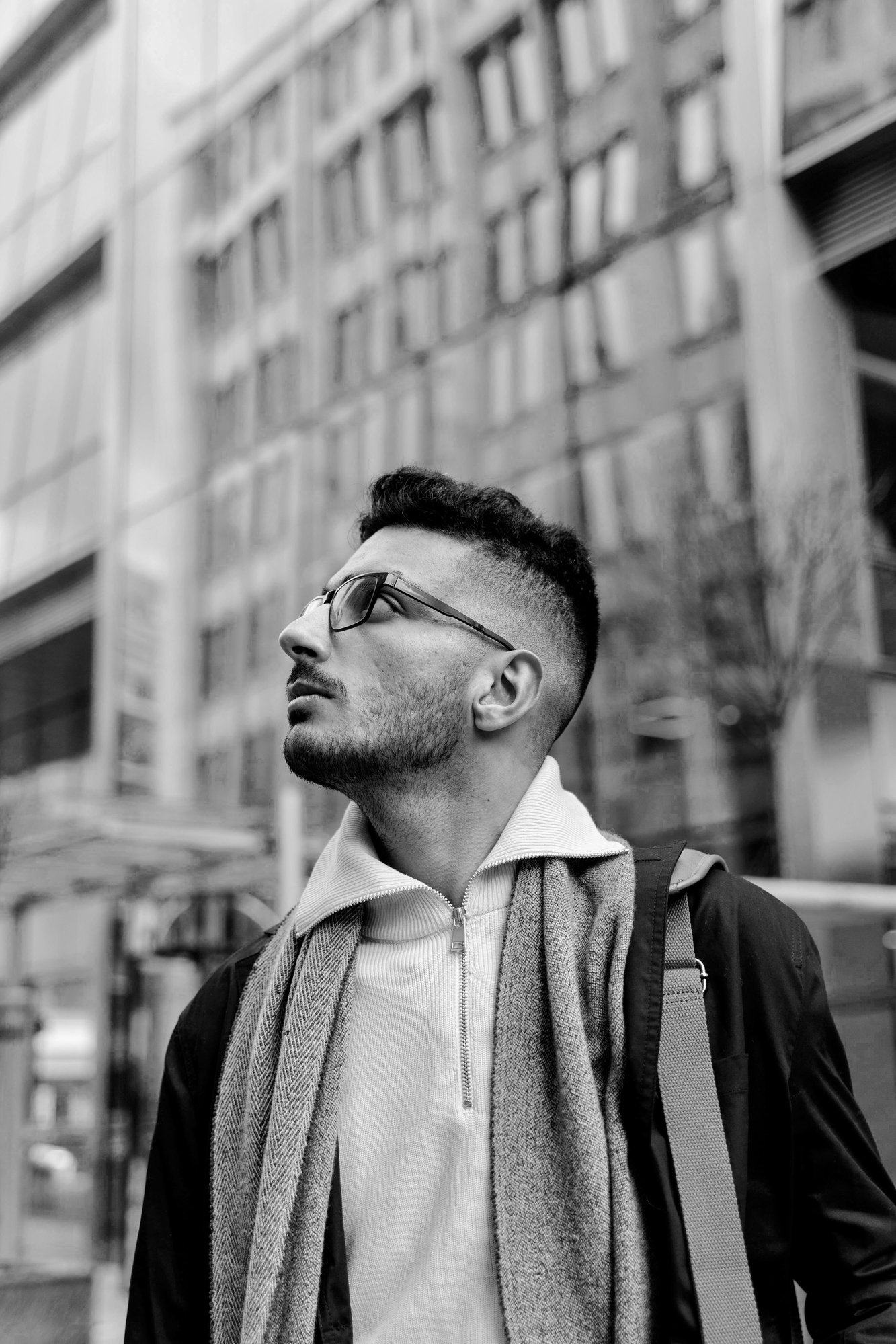 A man looking skyward, outside in a city environment